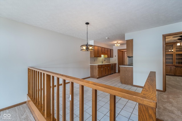 hall with a textured ceiling, baseboards, an inviting chandelier, and a sink