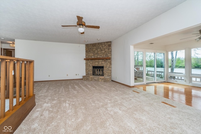 unfurnished living room featuring a ceiling fan, carpet, a textured ceiling, and a fireplace