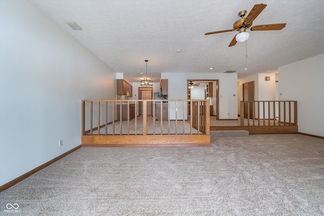 unfurnished living room with ceiling fan, a textured ceiling, carpet, baseboards, and visible vents