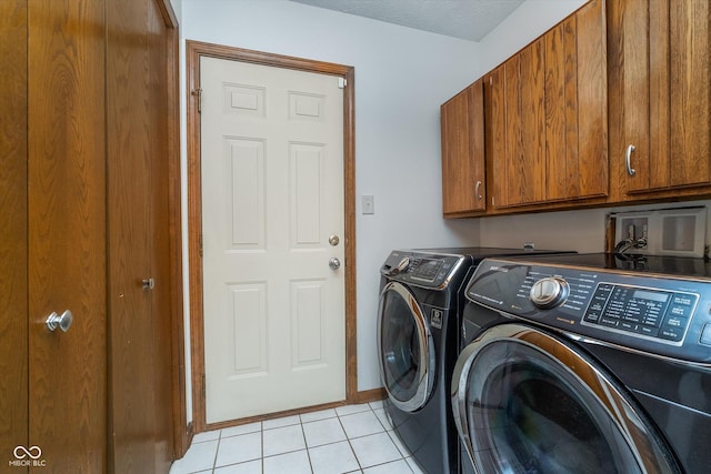 clothes washing area with light tile patterned floors, separate washer and dryer, baseboards, and cabinet space