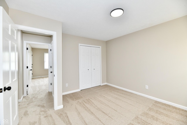 unfurnished bedroom featuring carpet flooring, baseboards, and a closet