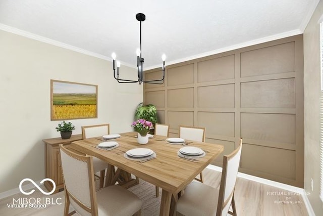 dining space with crown molding, an inviting chandelier, a decorative wall, baseboards, and light wood-type flooring