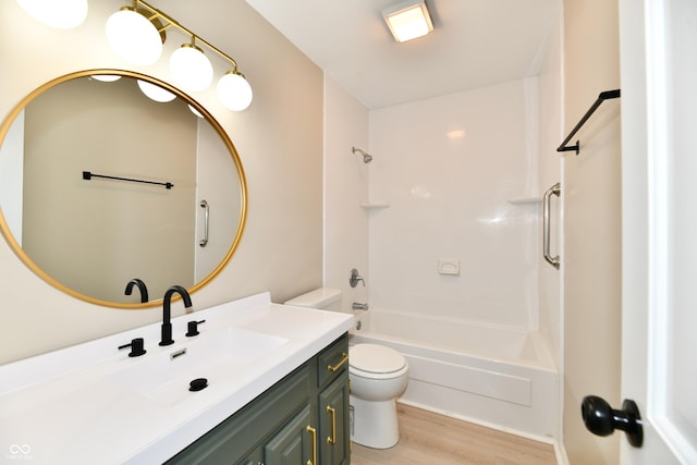 full bath featuring vanity, washtub / shower combination, wood finished floors, and toilet