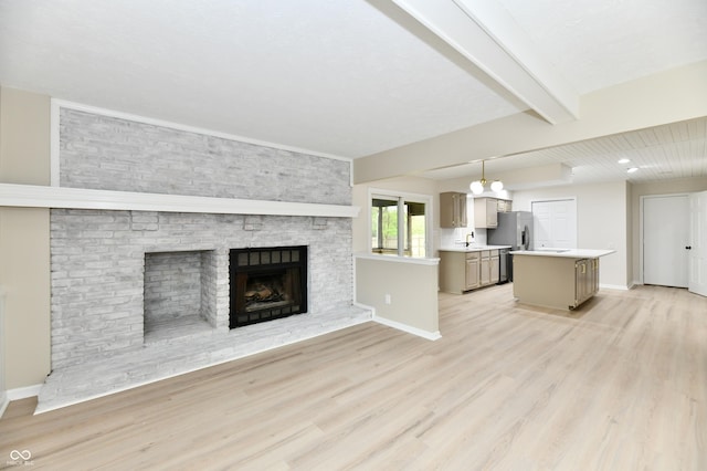 unfurnished living room featuring a sink, a fireplace, baseboards, light wood-type flooring, and beamed ceiling