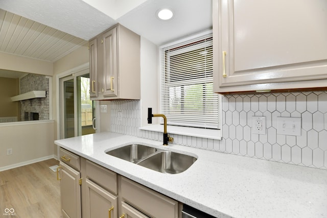 kitchen featuring a healthy amount of sunlight, a sink, light wood finished floors, and tasteful backsplash