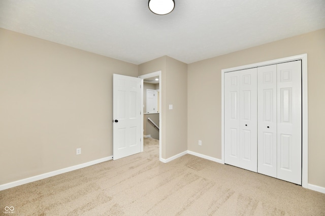 unfurnished bedroom featuring baseboards, carpet, and a closet