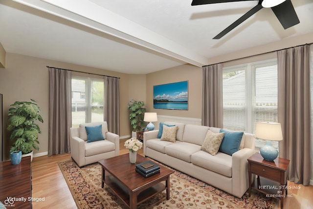 living area featuring ceiling fan, baseboards, beam ceiling, and light wood-style floors