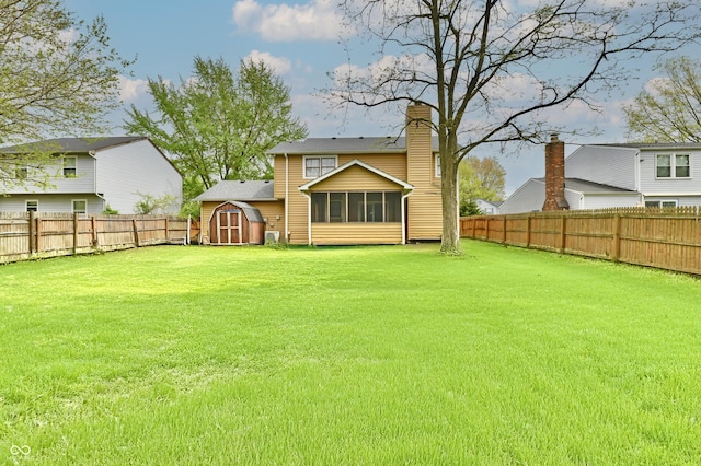 back of property with a lawn, a sunroom, a fenced backyard, an outdoor structure, and a shed