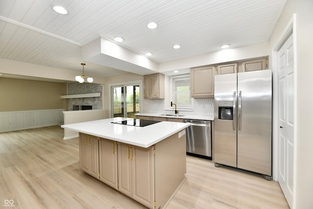 kitchen with appliances with stainless steel finishes, wainscoting, a sink, a center island, and light wood-type flooring