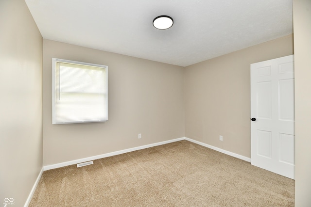 empty room featuring carpet floors, baseboards, and visible vents