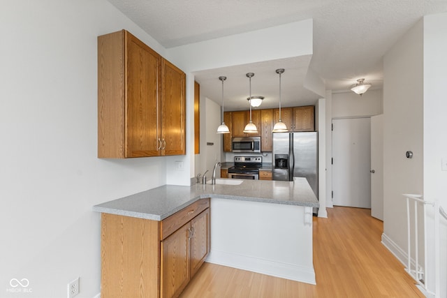kitchen with a sink, brown cabinets, stainless steel appliances, and a peninsula
