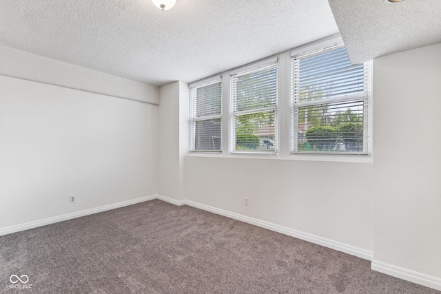 carpeted empty room featuring baseboards and a textured ceiling