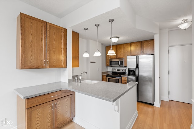kitchen with a sink, brown cabinets, stainless steel appliances, and a peninsula