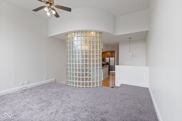 carpeted empty room with baseboards and a ceiling fan
