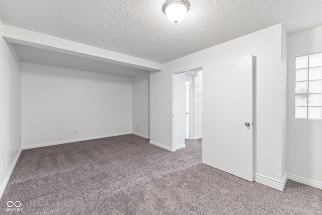 below grade area featuring carpet floors, a textured ceiling, and baseboards