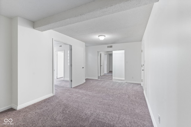 spare room with baseboards, carpet flooring, a textured ceiling, and visible vents