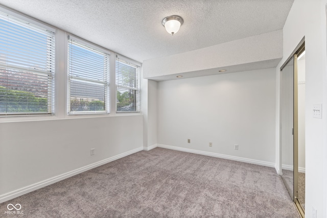 spare room featuring baseboards, a textured ceiling, and carpet