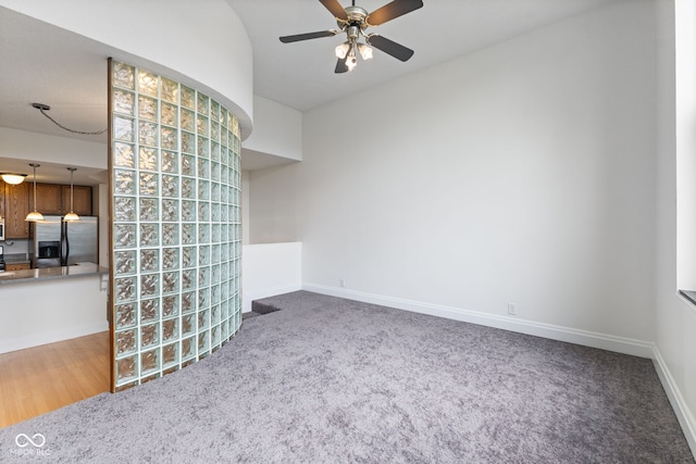 spare room with baseboards, ceiling fan, and carpet