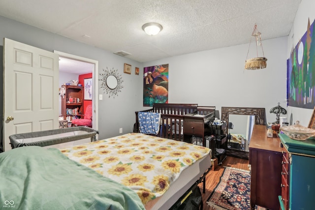 bedroom featuring visible vents, a textured ceiling, and wood finished floors