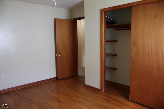 unfurnished bedroom with baseboards, a closet, and wood finished floors