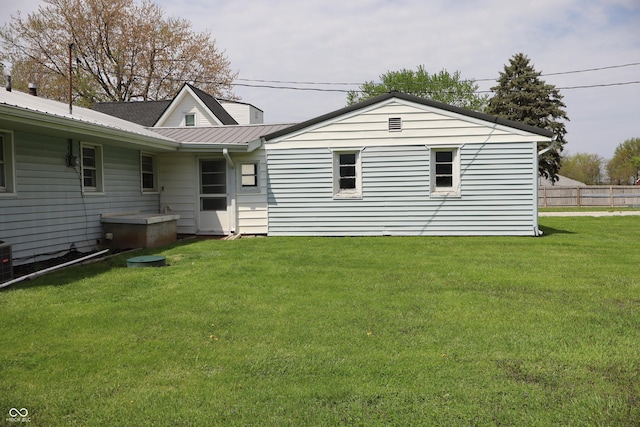 back of property with a lawn, fence, and metal roof