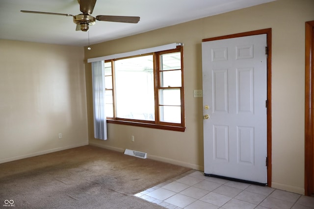 foyer entrance featuring baseboards, ceiling fan, light carpet, and visible vents