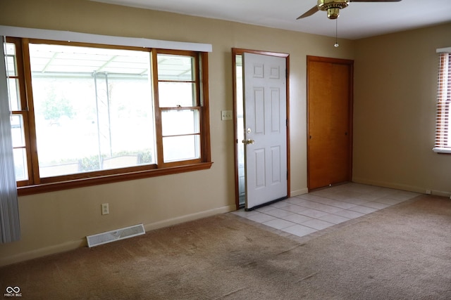 foyer featuring visible vents, a ceiling fan, a healthy amount of sunlight, and light carpet