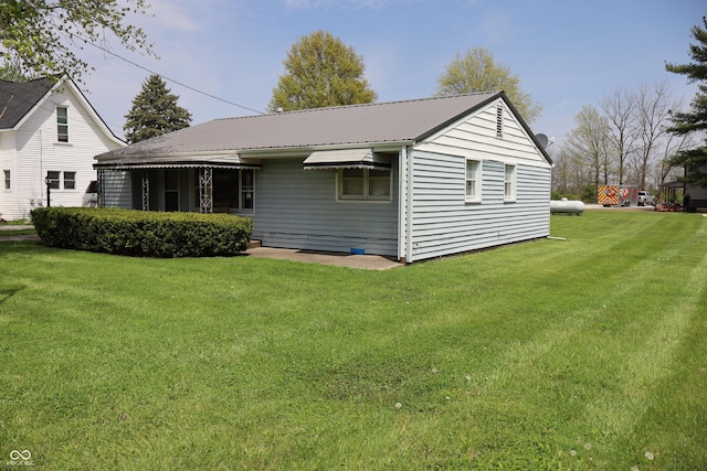 rear view of property featuring a yard and metal roof