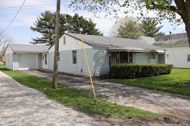 view of front of home with an attached garage, driveway, a front yard, and metal roof