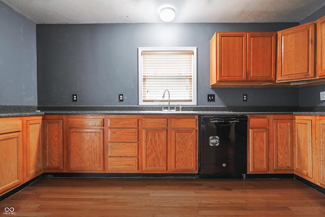 625 Maple St, Columbus, IN 47201 - kitchen with black dishwasher, a sink, wood finished floors, brown cabinetry, and a textured ceiling
