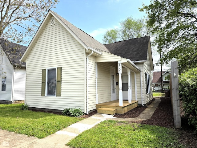 view of front of house with roof with shingles and a front yard