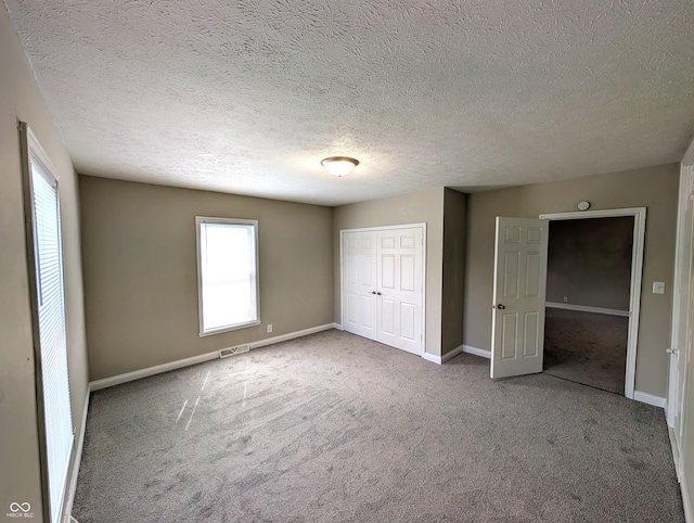 unfurnished bedroom featuring baseboards, multiple windows, carpet, and visible vents