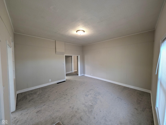 carpeted empty room featuring baseboards and a textured ceiling