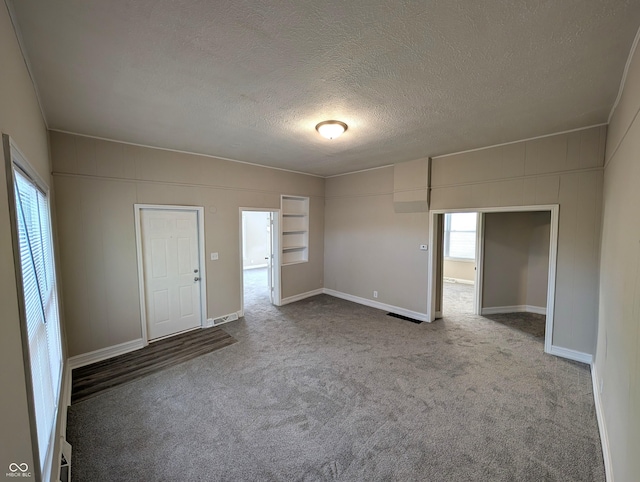 carpeted empty room featuring baseboards and a textured ceiling