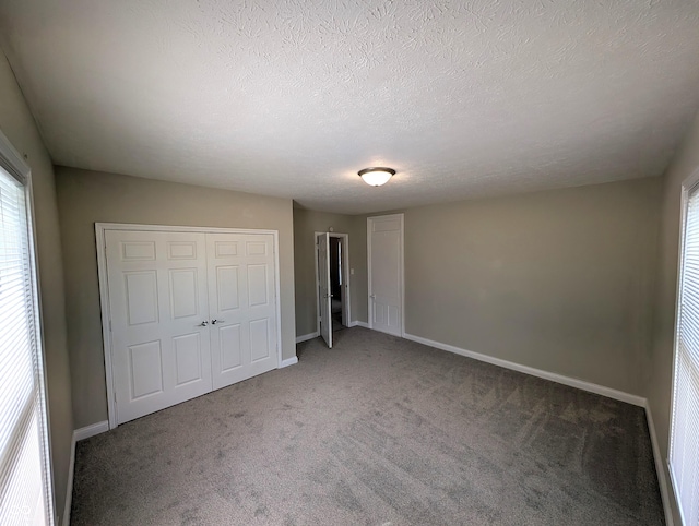 unfurnished bedroom with carpet floors, baseboards, multiple windows, and a closet