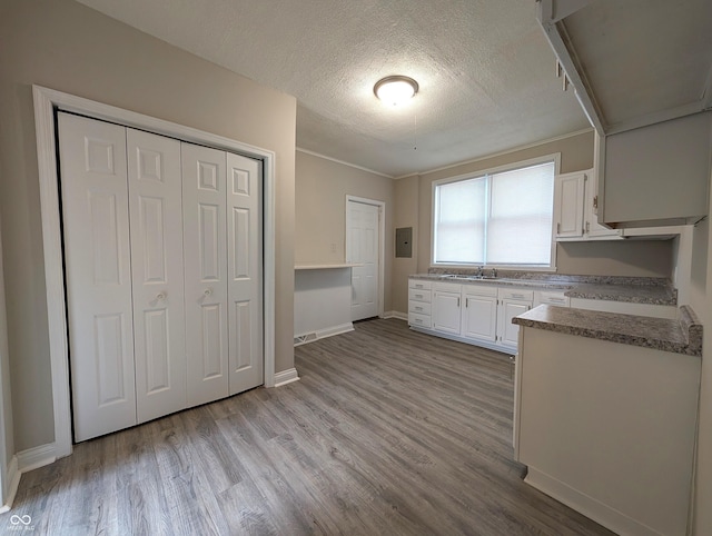 kitchen featuring a sink, white cabinets, light wood finished floors, and a textured ceiling