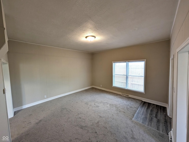 unfurnished room featuring visible vents, a textured ceiling, carpet, and baseboards