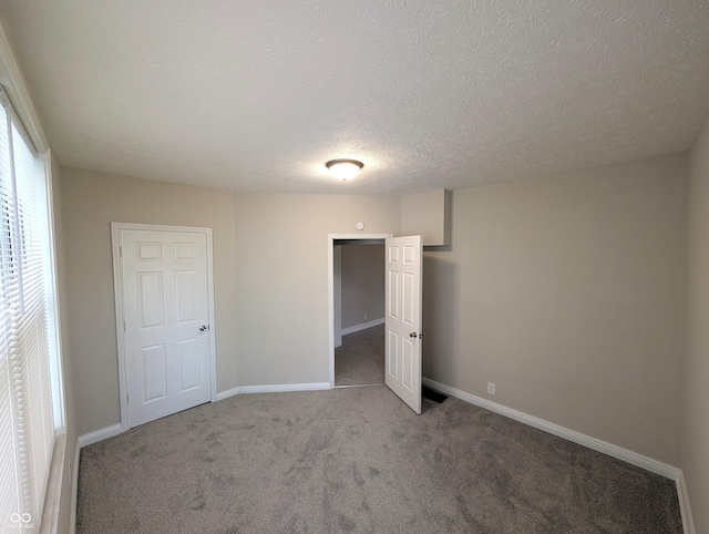 unfurnished bedroom featuring carpet flooring, a textured ceiling, and baseboards