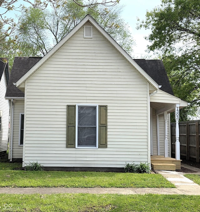 view of side of property with fence and a shingled roof