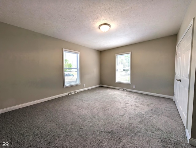 unfurnished bedroom with multiple windows, a textured ceiling, and visible vents