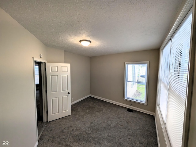 unfurnished room with dark carpet, a textured ceiling, and baseboards