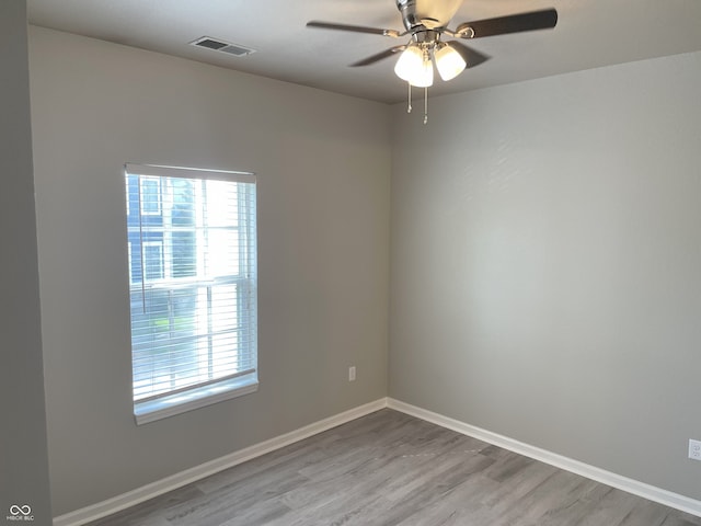 unfurnished room with ceiling fan, visible vents, a wealth of natural light, and wood finished floors