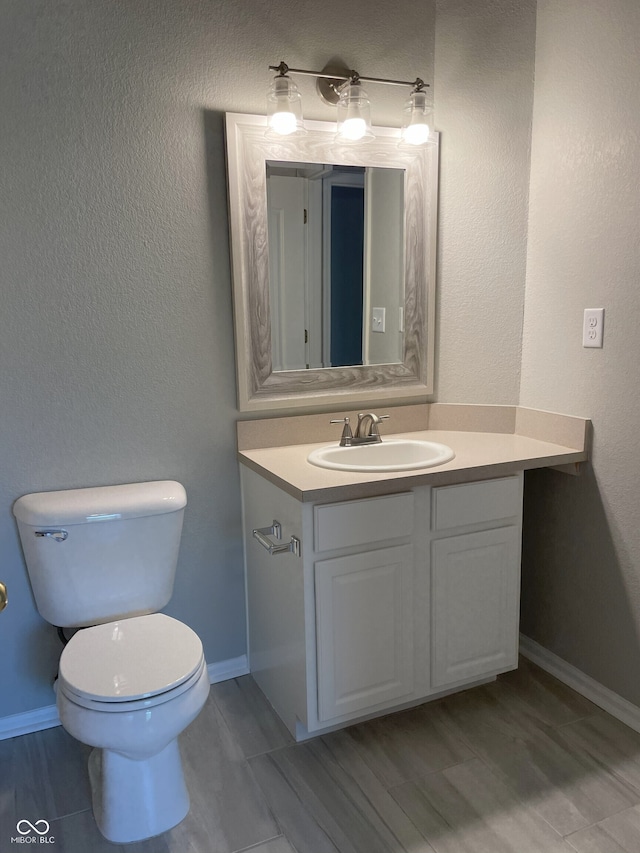 bathroom featuring toilet, baseboards, and vanity