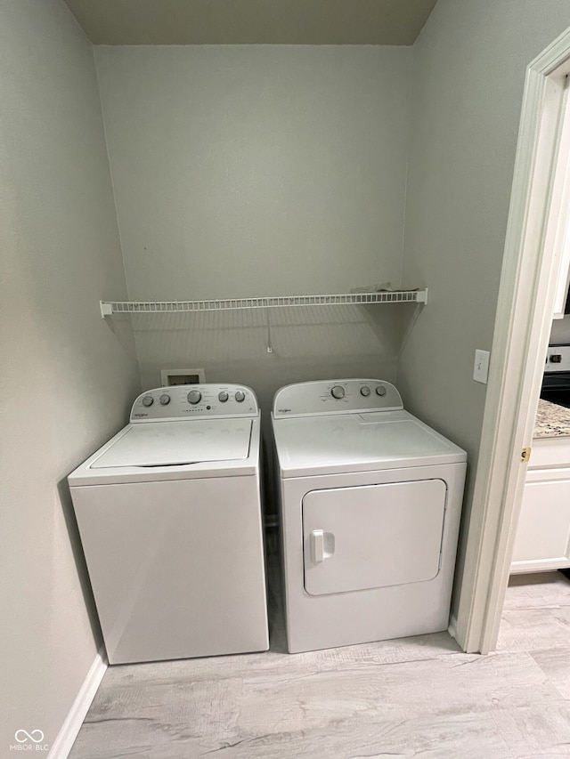 laundry area with separate washer and dryer, baseboards, wood finished floors, and laundry area