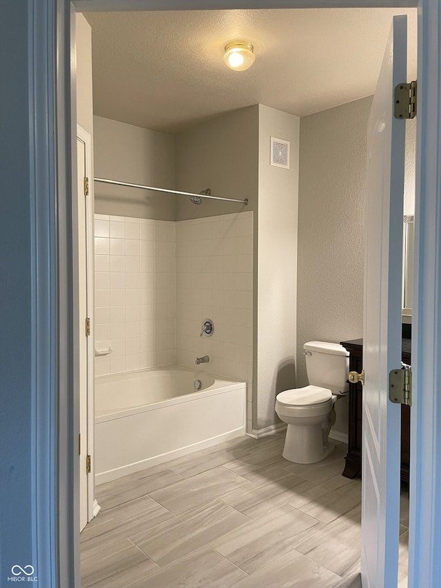 full bathroom featuring a textured wall, toilet, a textured ceiling, baseboards, and  shower combination