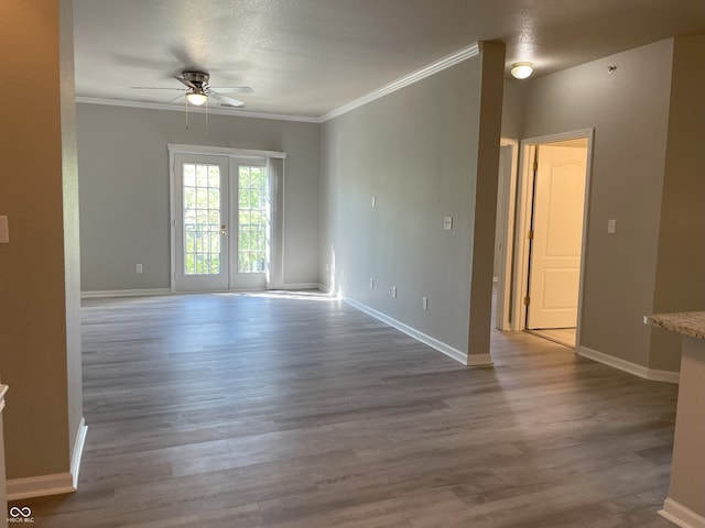 spare room with crown molding, a ceiling fan, baseboards, and wood finished floors