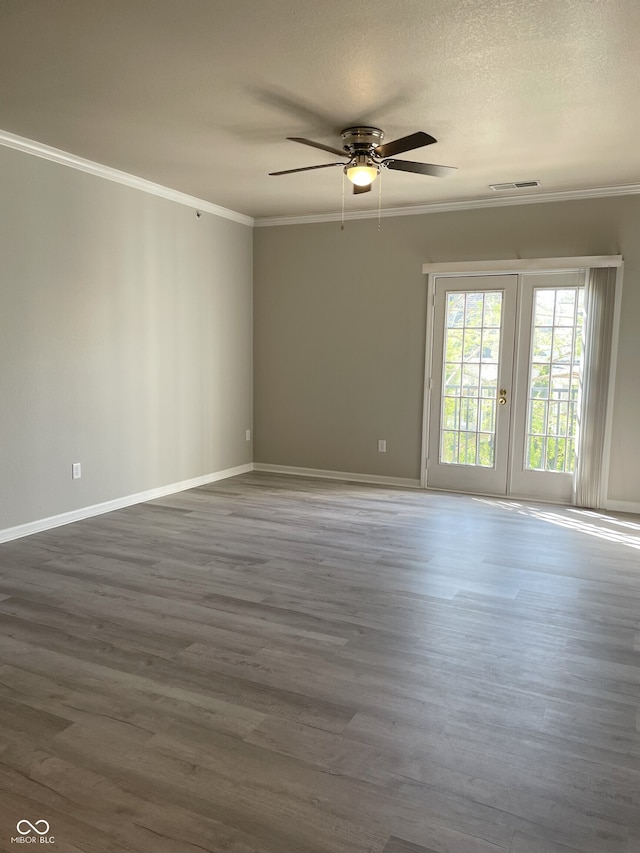 unfurnished room with ceiling fan, baseboards, wood finished floors, visible vents, and ornamental molding