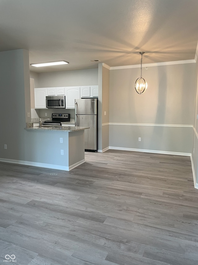 kitchen with crown molding, hanging light fixtures, wood finished floors, white cabinets, and stainless steel appliances