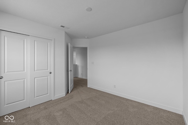 unfurnished bedroom with carpet floors, baseboards, a closet, and visible vents