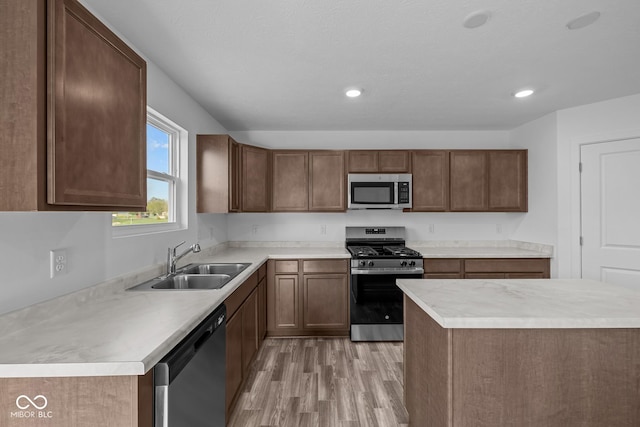 kitchen with light wood-type flooring, light countertops, recessed lighting, a sink, and stainless steel appliances